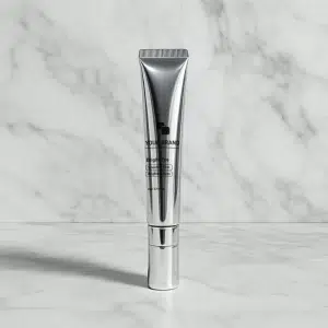 Sleek silver tube of 'Bright Eye' cream for smoothing, firming, and brightening, on a white marble surface.